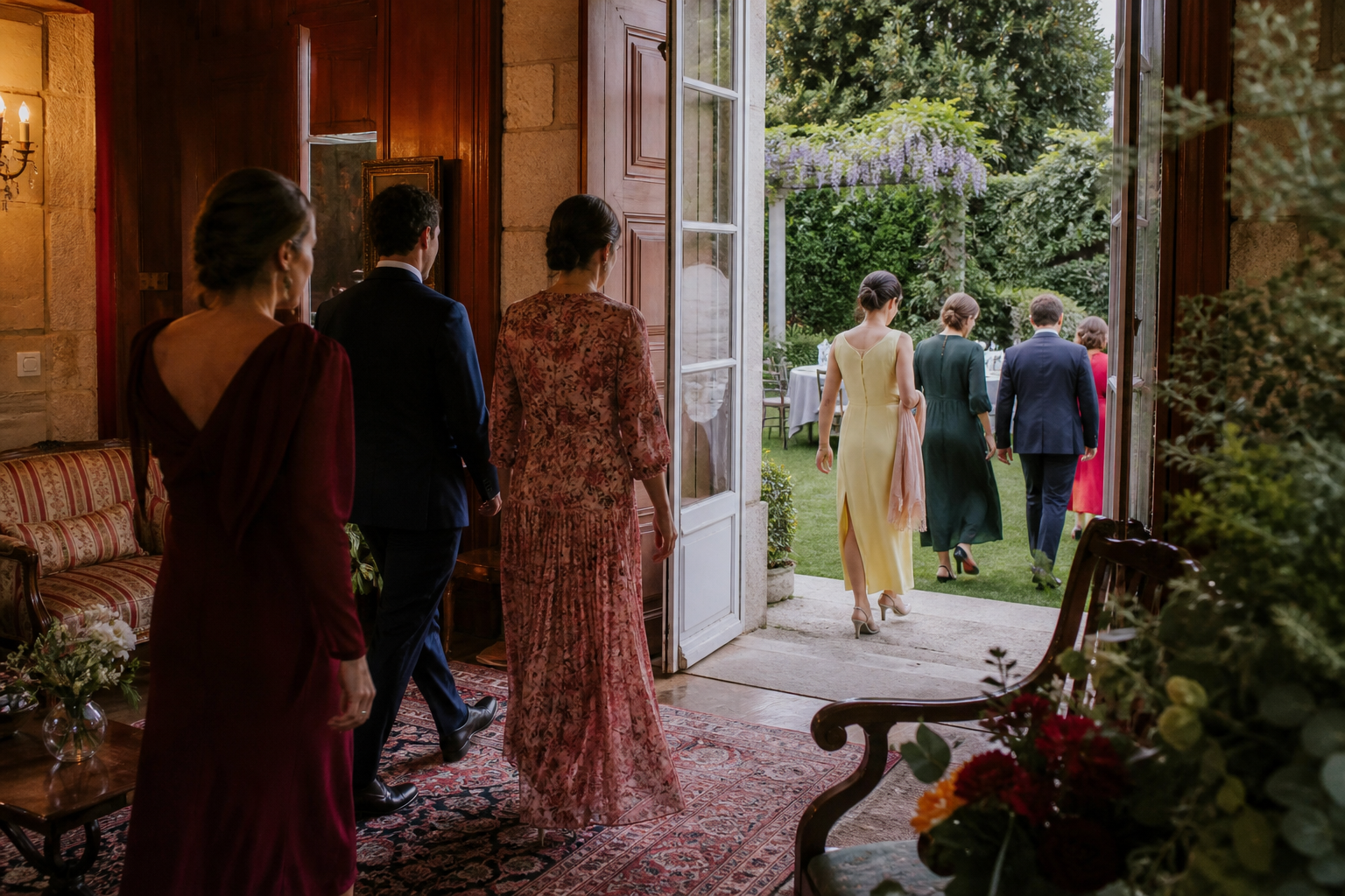 Invitados pasando de un salón histórico a un jardín durante una celebración