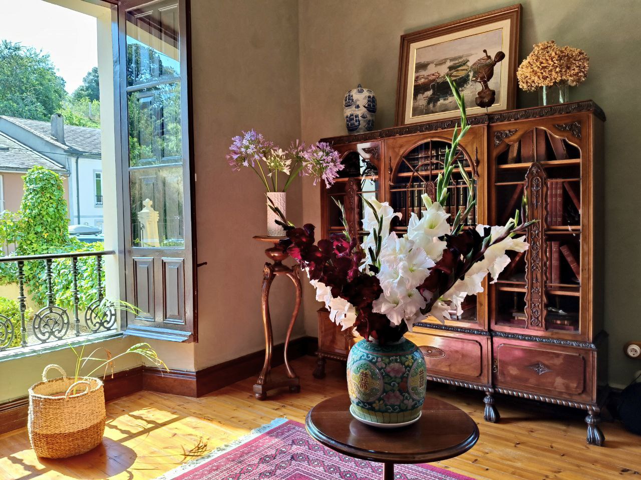 Salón real de Palacio Santa Emilia con biblioteca, flores y balcón abierto