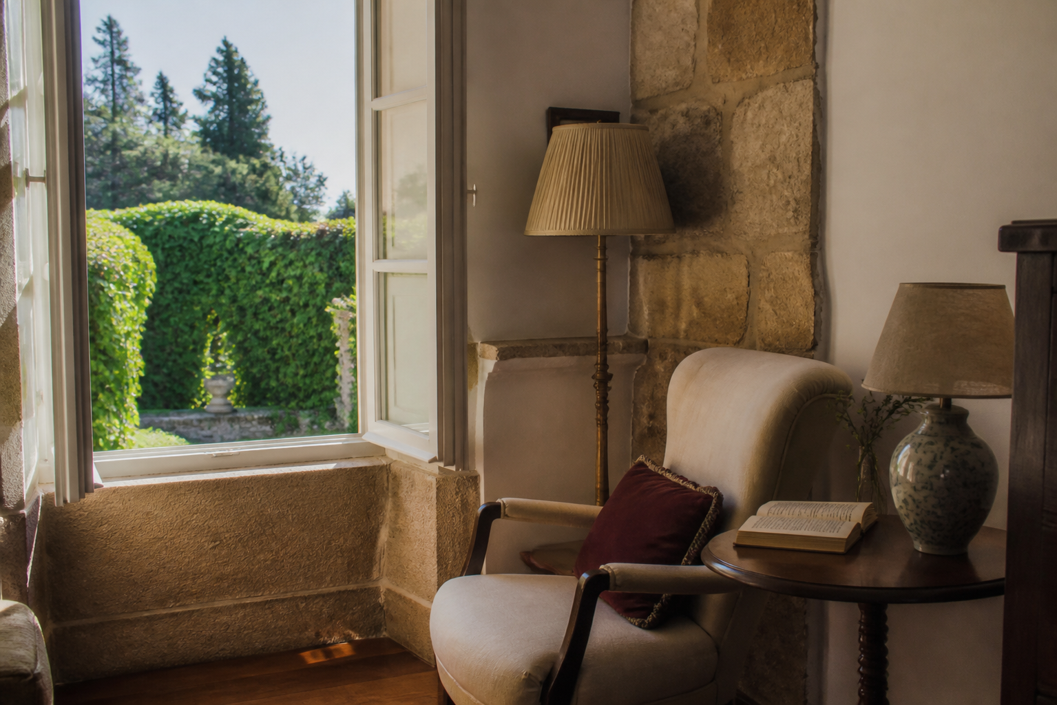 Rincón de lectura junto a una ventana abierta al jardín en una estancia histórica