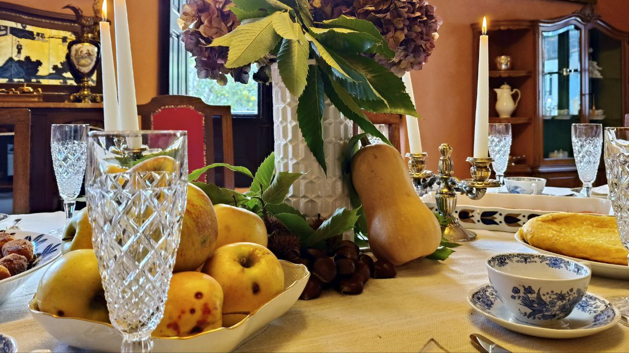 A seasonal dining table with fruit, chestnuts, candles and patterned china inside Santa Emilia
