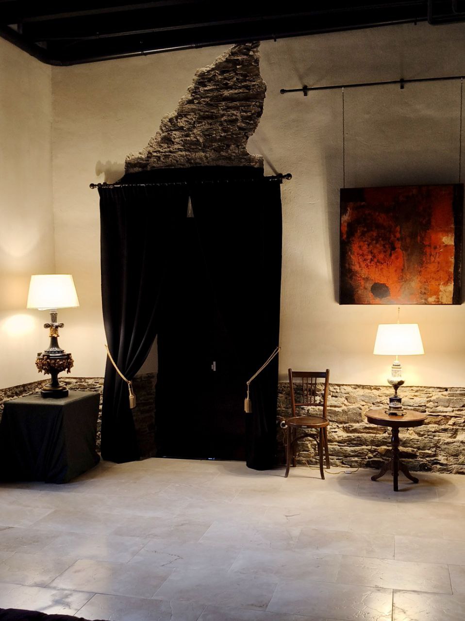 Salón de los Pilares en Santa Emilia con piedra, lámparas y cortinas oscuras