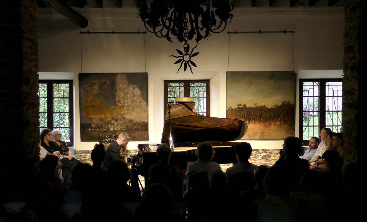 Audience listening to a piano recital in the Salón de los Pilares at Santa Emilia